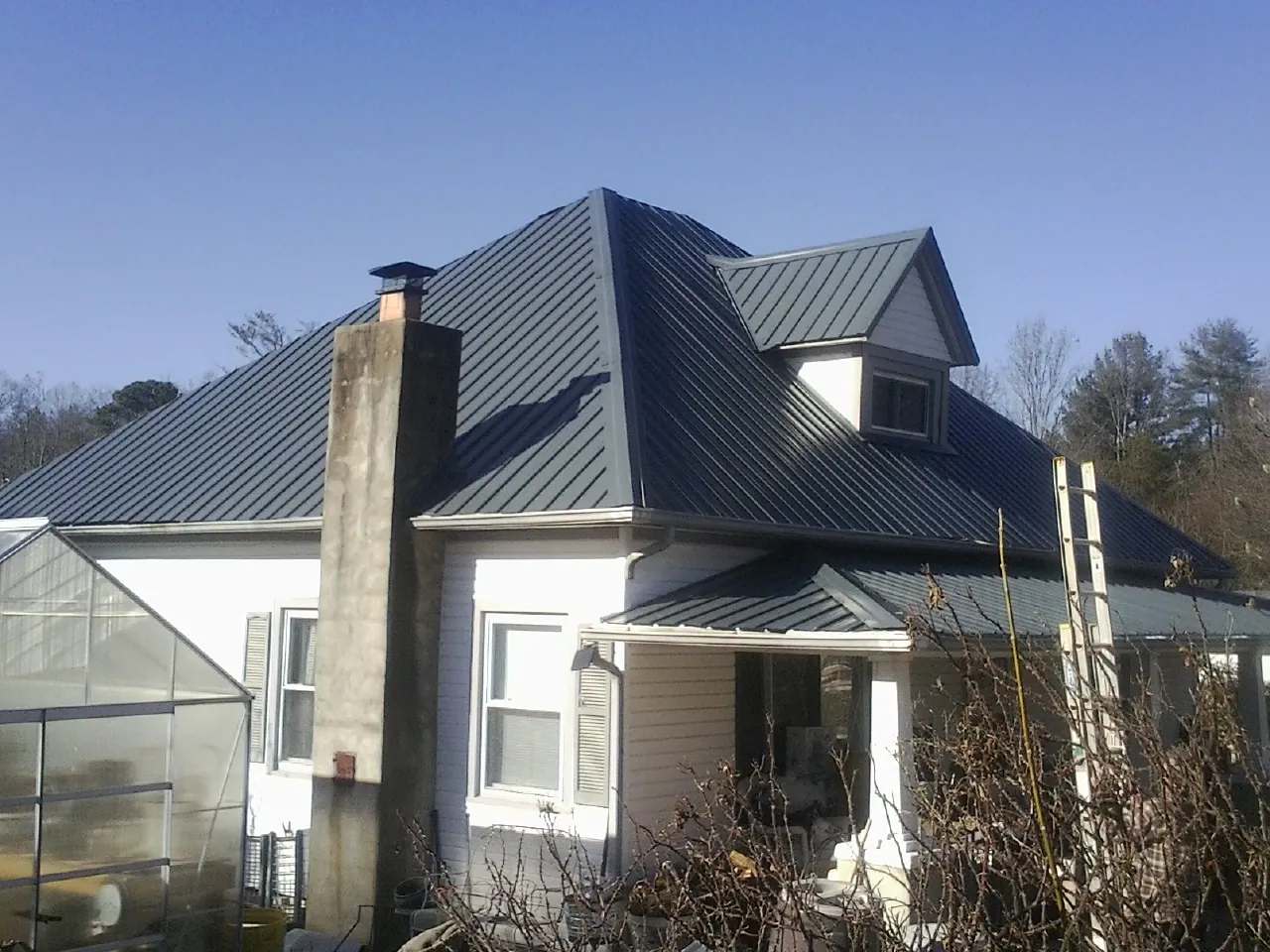 Dark blue standing seam metal roof on a white farmhouse with dormer — Slate & Tile Roof Repair by Roofing Brothers in Forest Grove