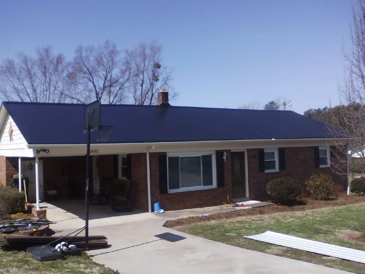Finished dark blue metal roof on a brick ranch with a carport in Forest Grove
