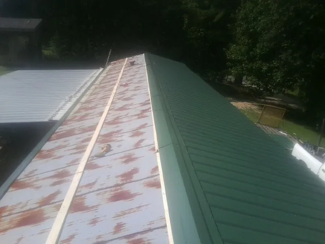 Old rusted panels beside newly installed green metal roofing — Wind Damage Roof Repair by Roofing Brothers in Forest Grove