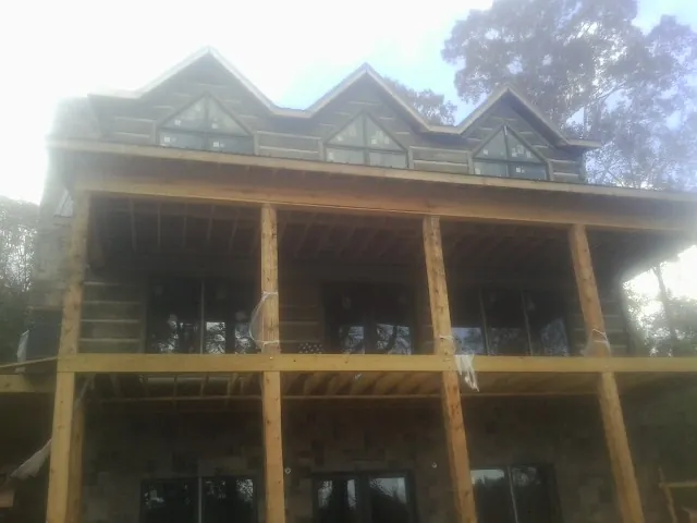 Dormers and porch framing on a large log home under construction — Roof Coating work by our crew in Forest Grove