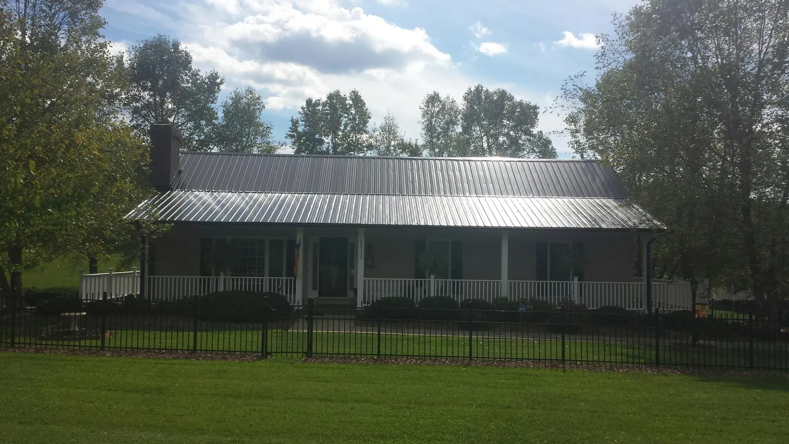Gray metal roof on a brick ranch with a full width front porch — Gutter Guard Installation work by our crew in Forest Grove