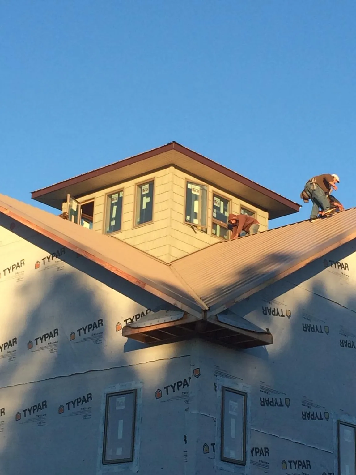 Roofers working around a rooftop cupola on a new metal roof at sunset — Roof Waterproofing in Forest Grove by Roofing Brothers